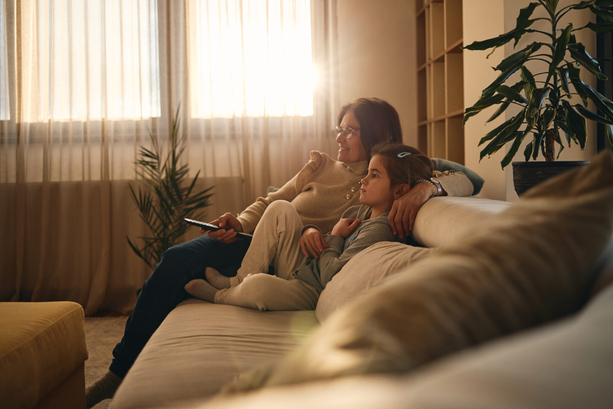 äiti ja tytär istuvat sohvalla ja katsovat televisiota