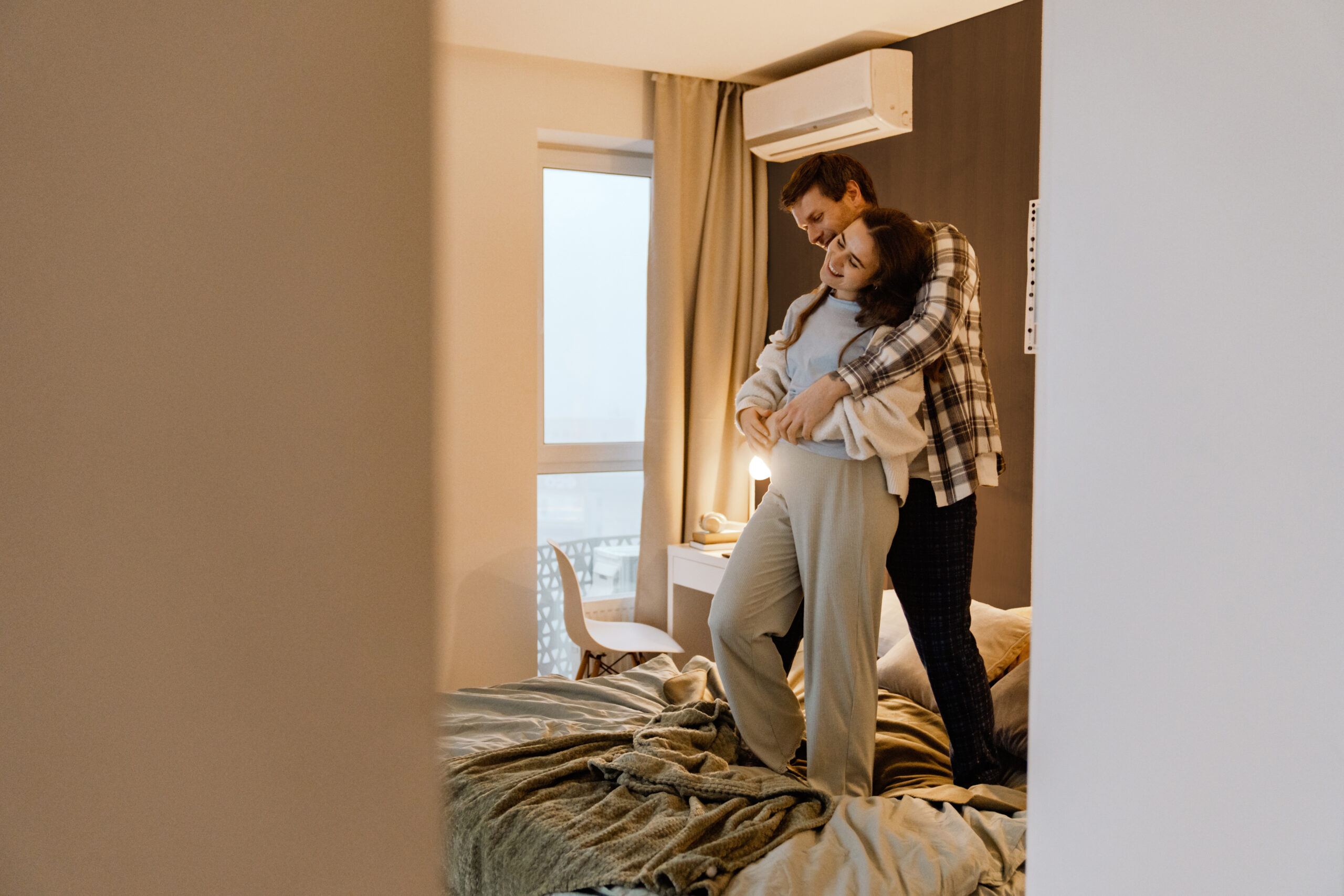 man and a woman hug while standing on a bed