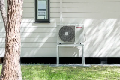 Toshiba luftvärmepump installerad på ytterväggen till ett garage.